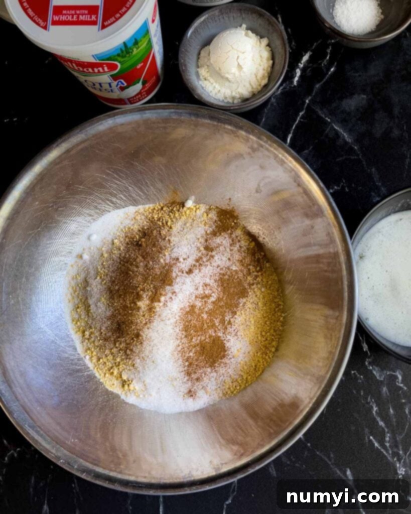 Dry ingredients for the graham cracker crust in a metal bowl, including crumbs, cinnamon, and salt.