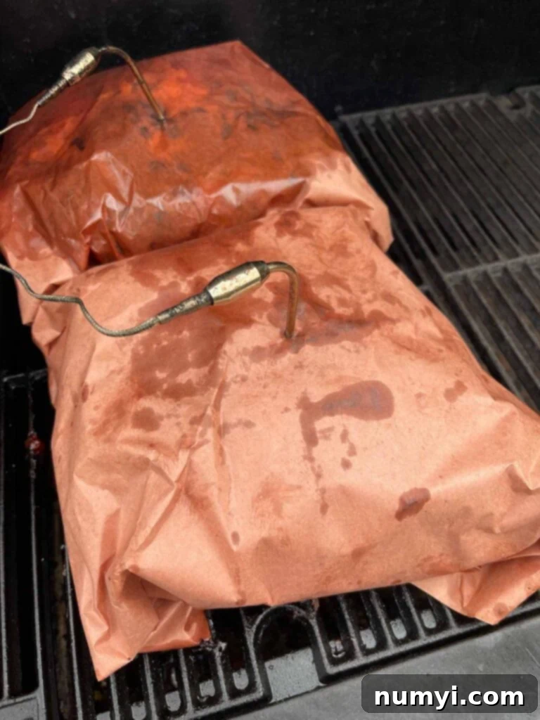 Two pork butts wrapped in butcher paper.