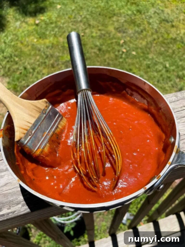 bourbon chipotle barbecue sauce in a saucepan with a whisk and brush.