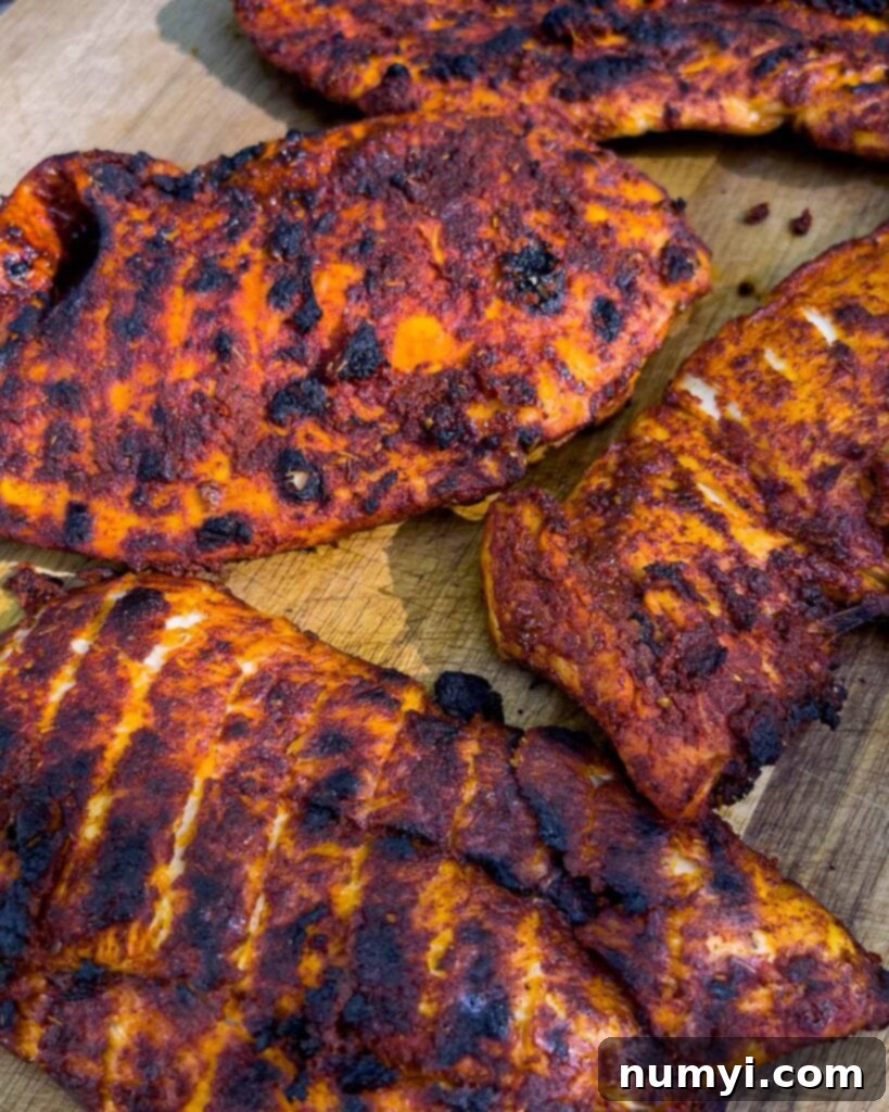 Grilled Mexican chicken breasts, fresh off the grill and resting, showing off perfectly seared surfaces.