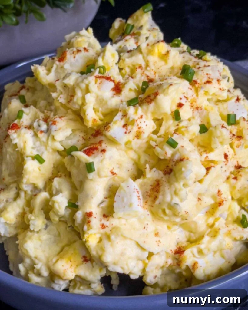 Southern potato salad in a bowl garnished with chives and paprika, ready to be served at a family gathering or barbecue.