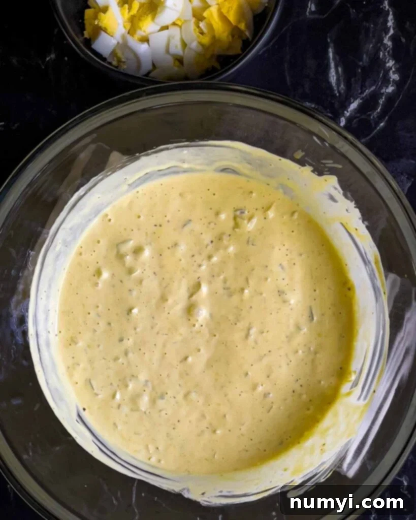 All Southern potato salad dressing ingredients combined in a large glass mixing bowl, ready for potatoes.