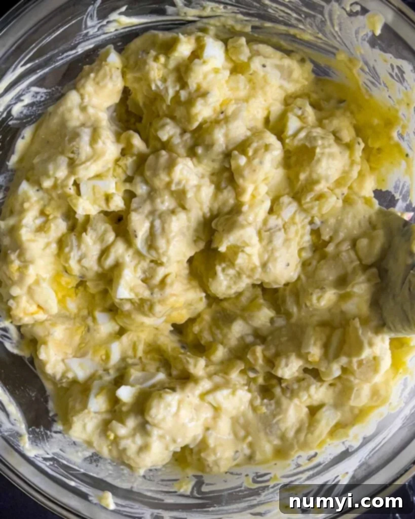 Southern potato salad perfectly combined in a glass mixing bowl, showcasing its creamy texture.