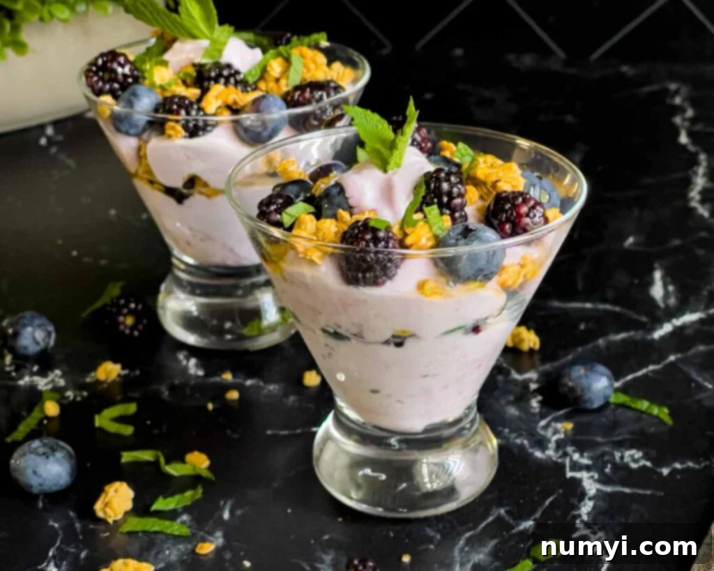 Refreshing Berry Yogurt Parfait 2 Berry yogurt parfait in a stemless martini glass on a dark surface.