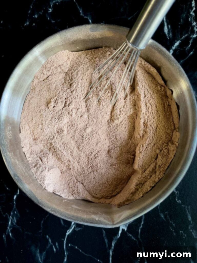 The Easiest Mississippi Mud Cake 5 Dry ingredients for Mississippi Mud Cake whisked together in a metal bowl.