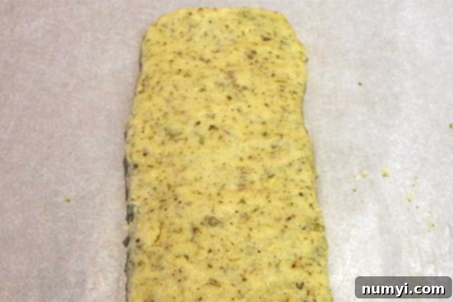 Biscotti dough expertly formed into a long log on parchment paper, ready for the first bake.