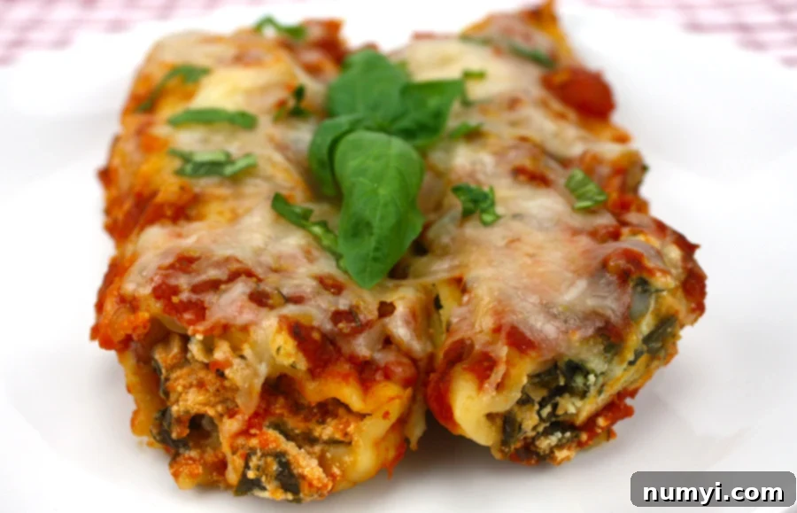 Slow Cooker Spinach Ricotta Manicotti on a white plate garnished with fresh basil leaves, ready to be served.