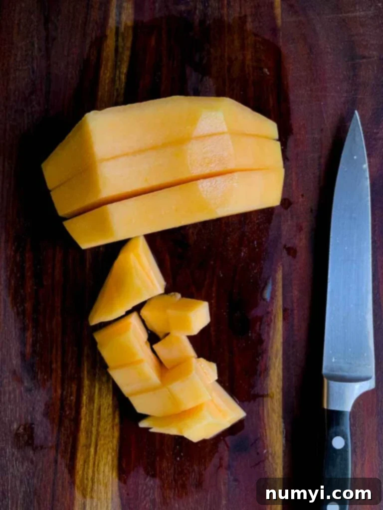 Mixed Melon Fruit Salad with Honey Lime and Mint 5 Perfectly diced cantaloupe cubes neatly arranged on a dark wooden cutting board, ready for the fruit salad.