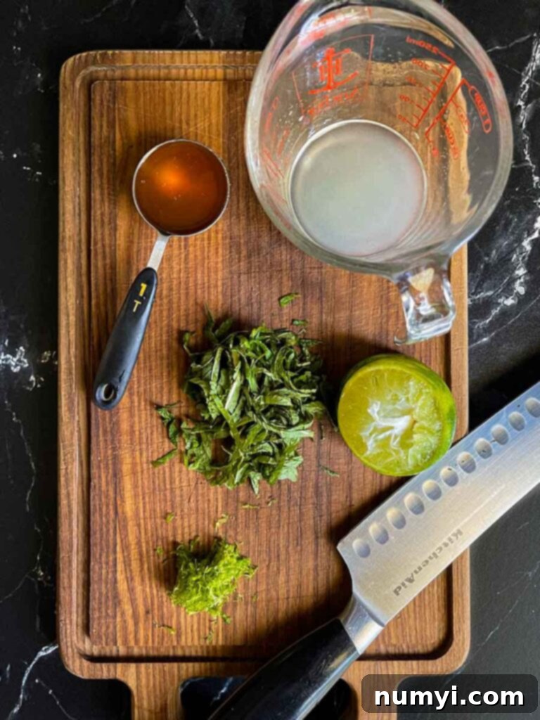 Mixed Melon Fruit Salad with Honey Lime and Mint 7 The vibrant ingredients for the honey-lime mint dressing, including freshly squeezed lime juice, bright green lime zest, golden honey, and finely chopped fresh mint, displayed on a dark cutting board.