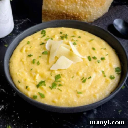 Polenta in a dark bowl garnished with chopped parsley and parmesan cheese.