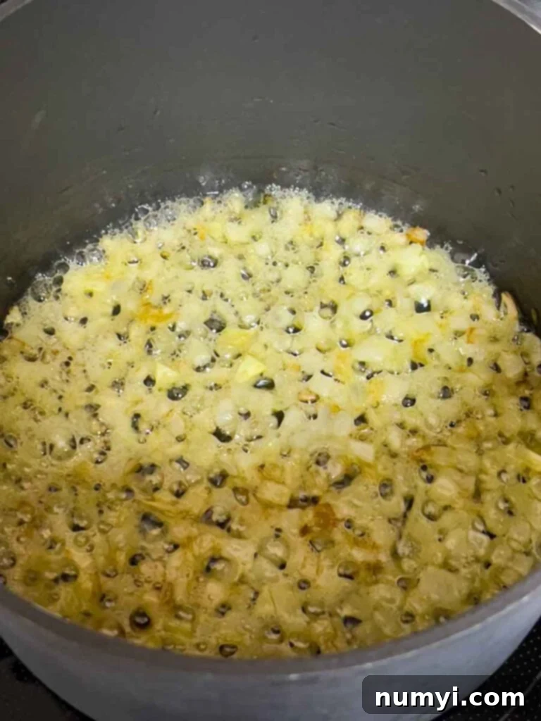 Diced onions being sauteed in a pot with olive oil.