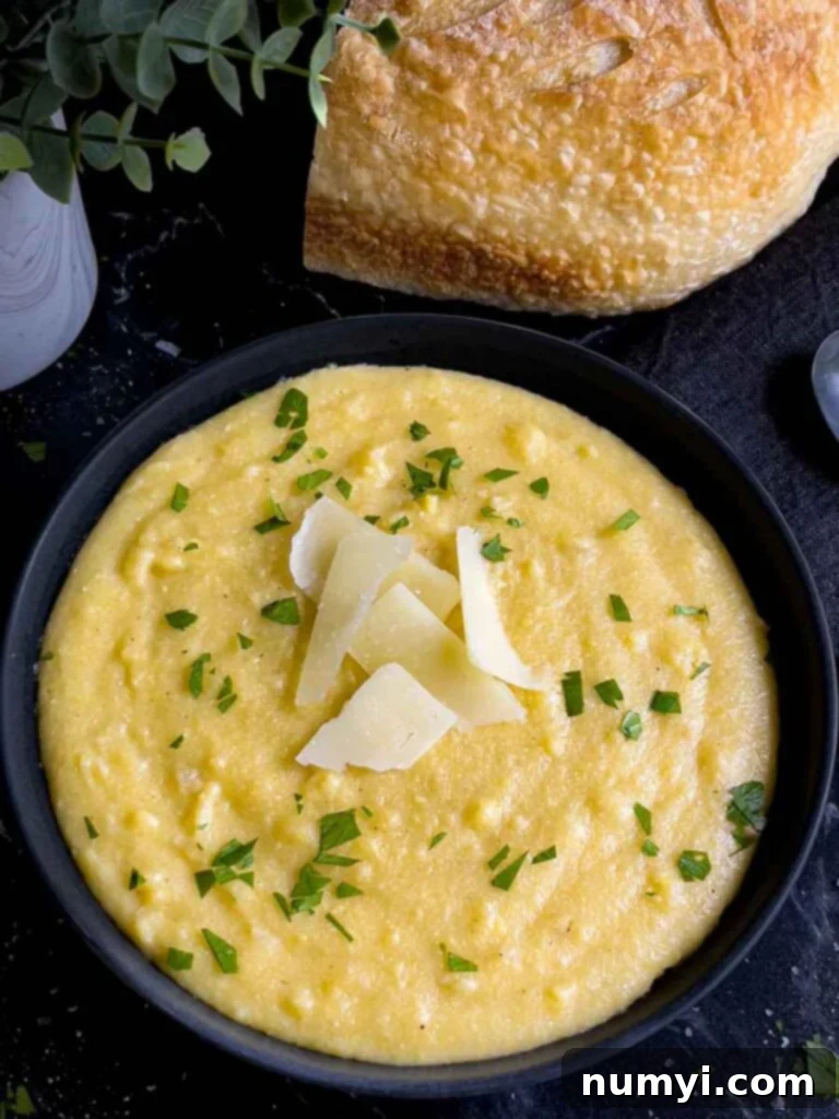 Polenta in a dark bowl garnished with chopped parsley and parmesan cheese.