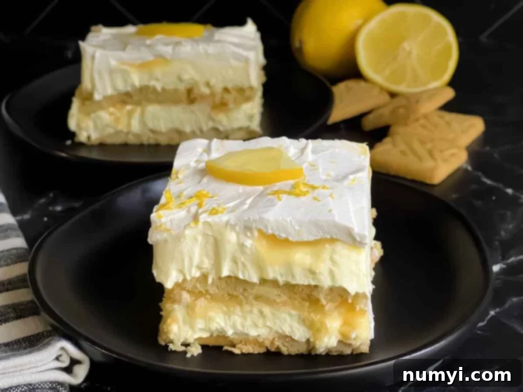 A serving of Lemon Icebox cake garnished with a lemon slice and zest on a dark plate.