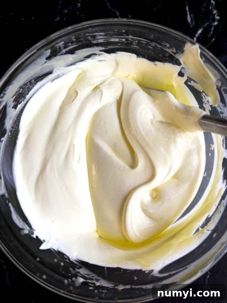 The pudding filling for the lemon icebox cake in a glass mixing bowl on a dark surface.