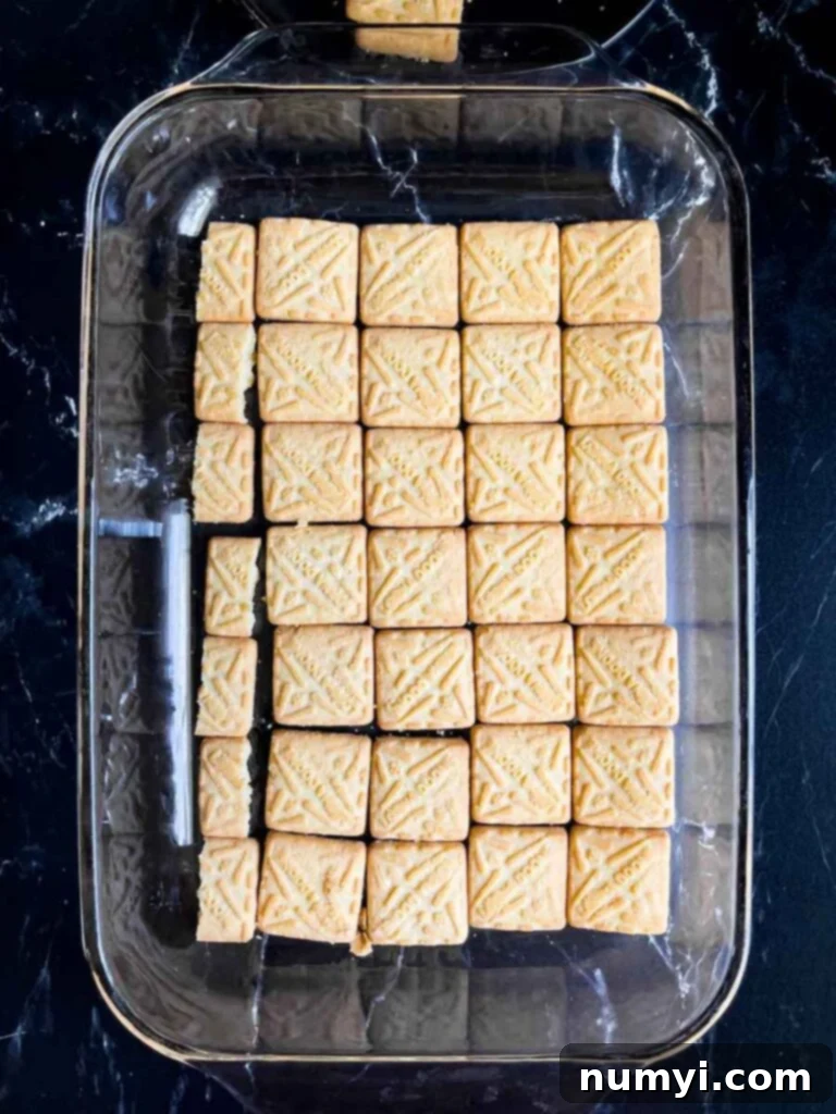 Shortbread cookies in a single layer in the bottom of a glass baking dish on a dark surface.