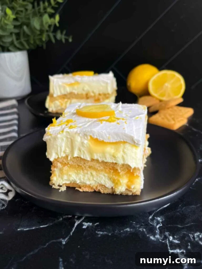 A serving of Lemon Icebox cake garnished with a lemon slice and zest on a dark plate.