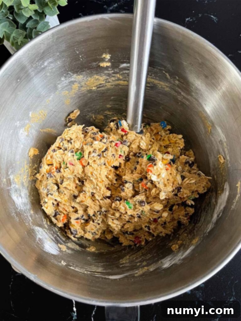 Monster cookie dough in a metal mixing bowl after all ingredients have been combined.