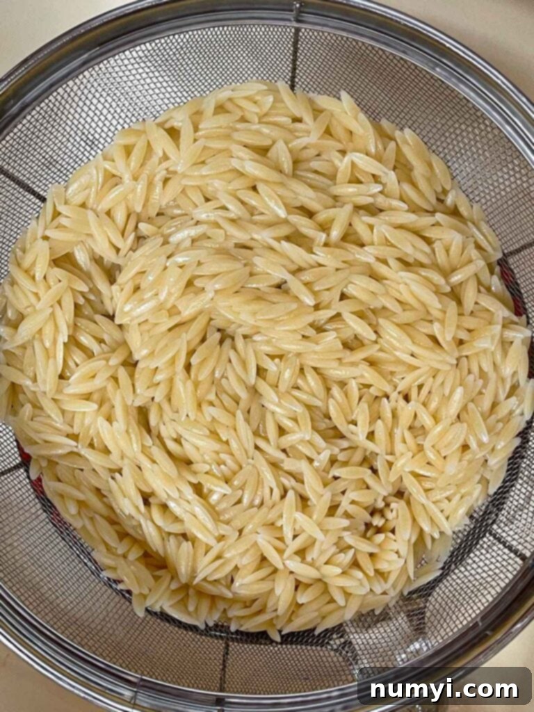 Cooked and drained orzo in a mesh strainer for the spinach and feta orzo salad.
