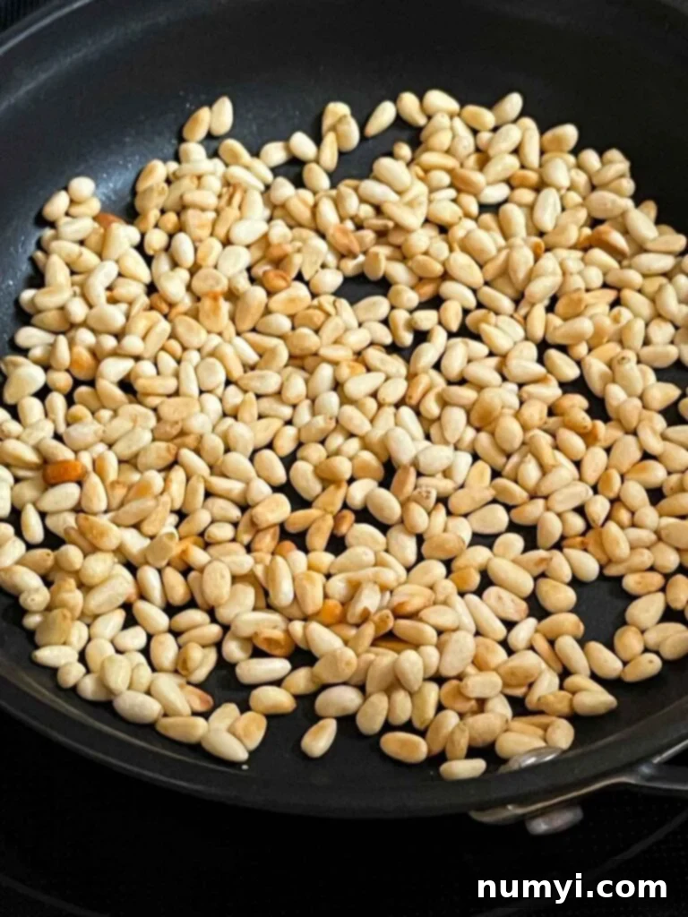 Toasted pine nuts in a dry skillet for the spinach and feta orzo salad.