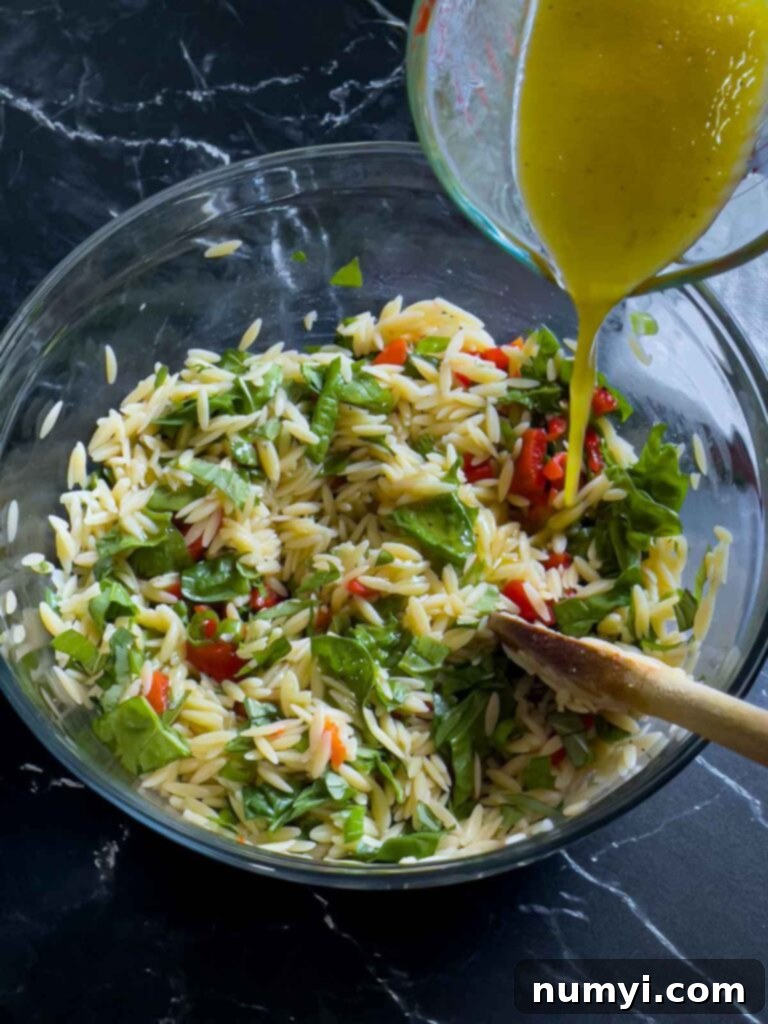 Dressing being added to the spinach and feta orzo salad.