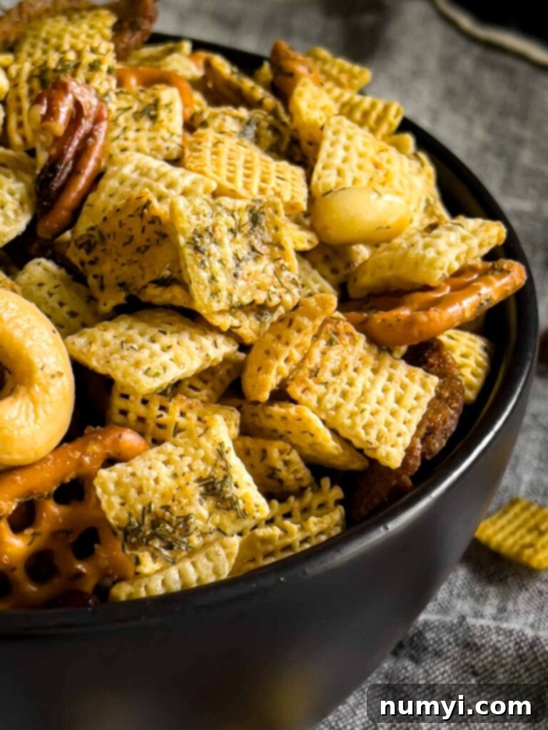 Tangy Dill Chex Crunch 8 Dill Pickle Chex Mix in a small dark bowl on a light linen napkin, tempting to eat.