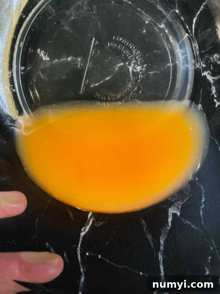 Accumulated peach juices at the bottom of a glass bowl, drained from the sliced peaches.