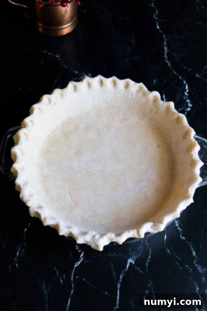 Fluted pie dough on a dark surface.
