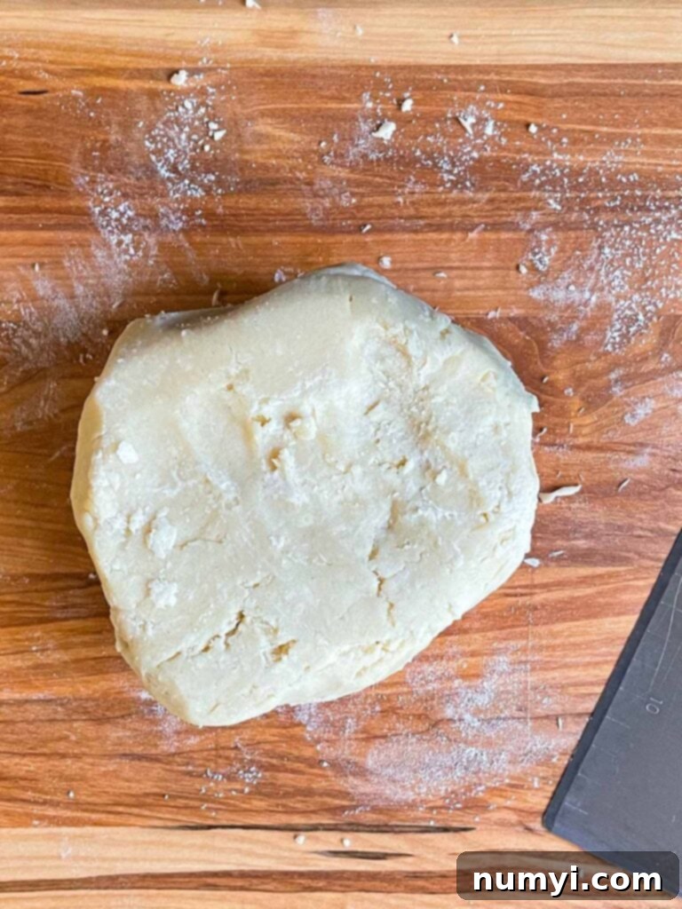 Pie crust dough on a wooden cutting board.