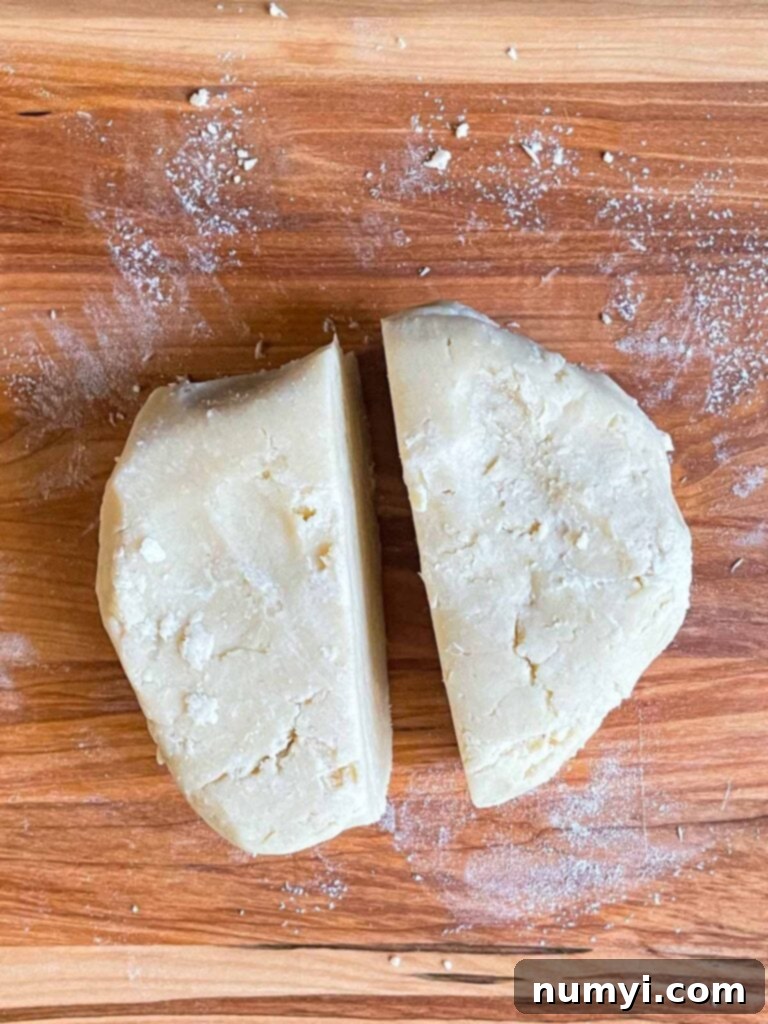 Pie crust dough divided on a cutting board.
