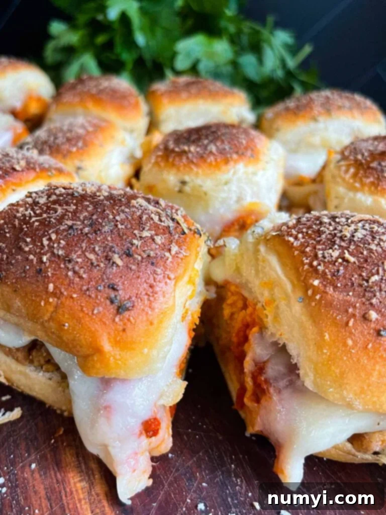 Chicken parmesan sliders on a wooden cutting board, ready to serve.
