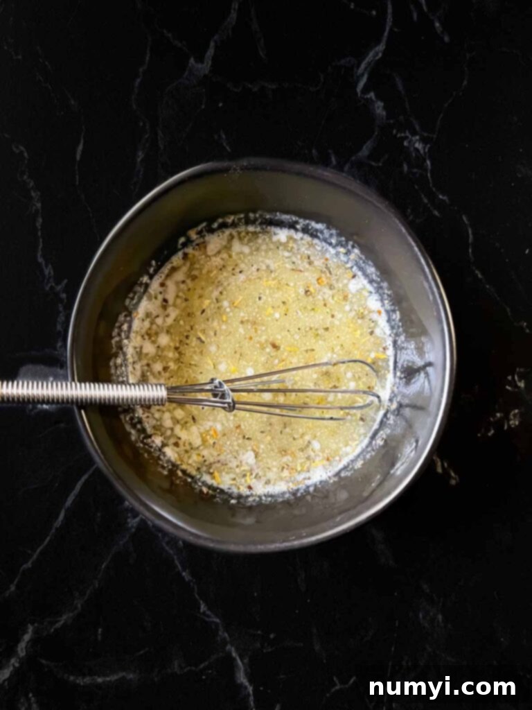 A small bowl containing melted butter, Italian seasoning, and garlic powder.