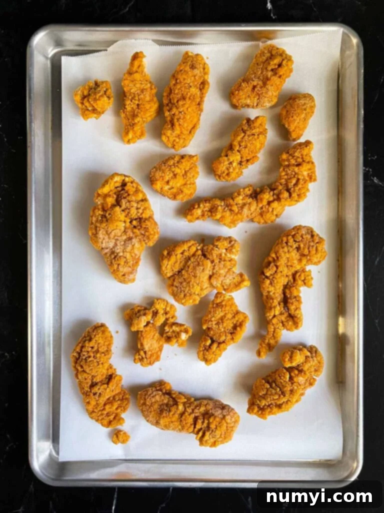 Baked chicken tenders on a parchment-lined baking sheet.