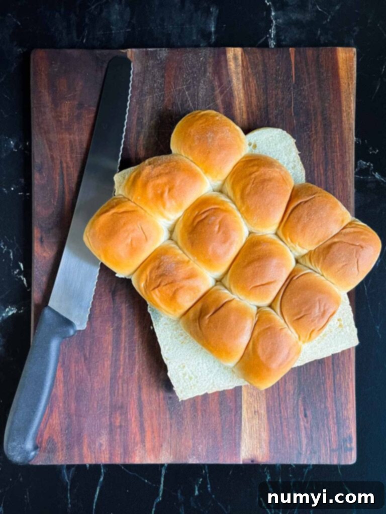 Slider rolls sliced horizontally on a dark cutting board.