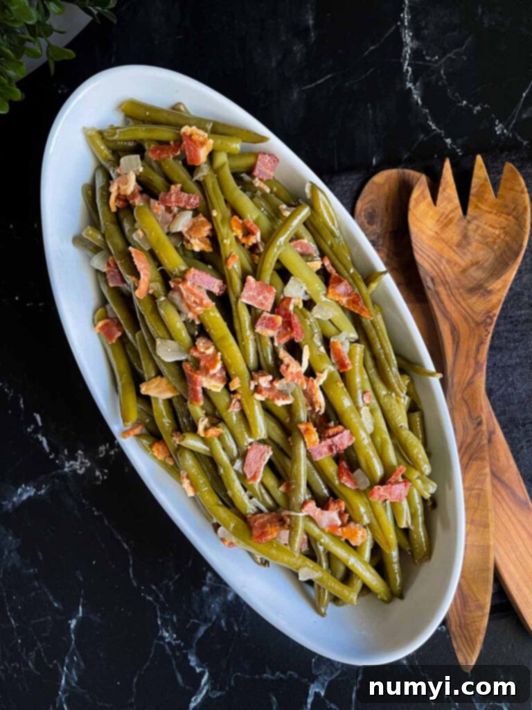 Slow cooker green beans in a white serving bowl on a dark surface.
