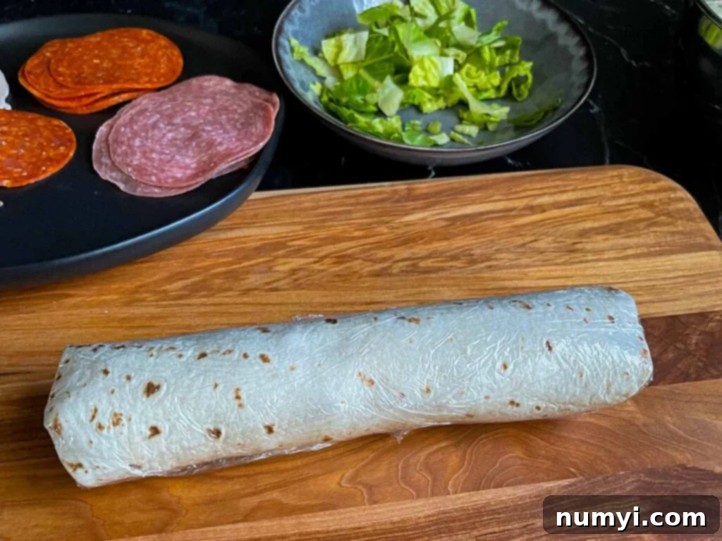 An Italian pinwheel, tightly wrapped in plastic wrap and chilled, awaiting slicing.