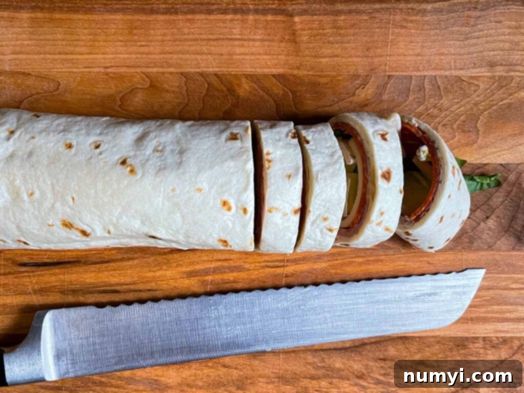 Slicing the Italian wrap into individual pinwheels with a serrated knife.
