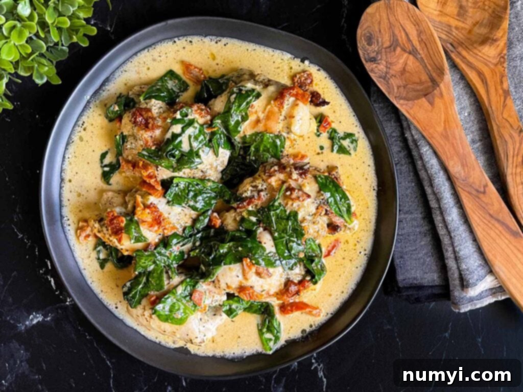 Creamy Slow Cooker Tuscan Chicken 2 Slow Cooker Tuscan Chicken in a dark bowl on a dark surface.