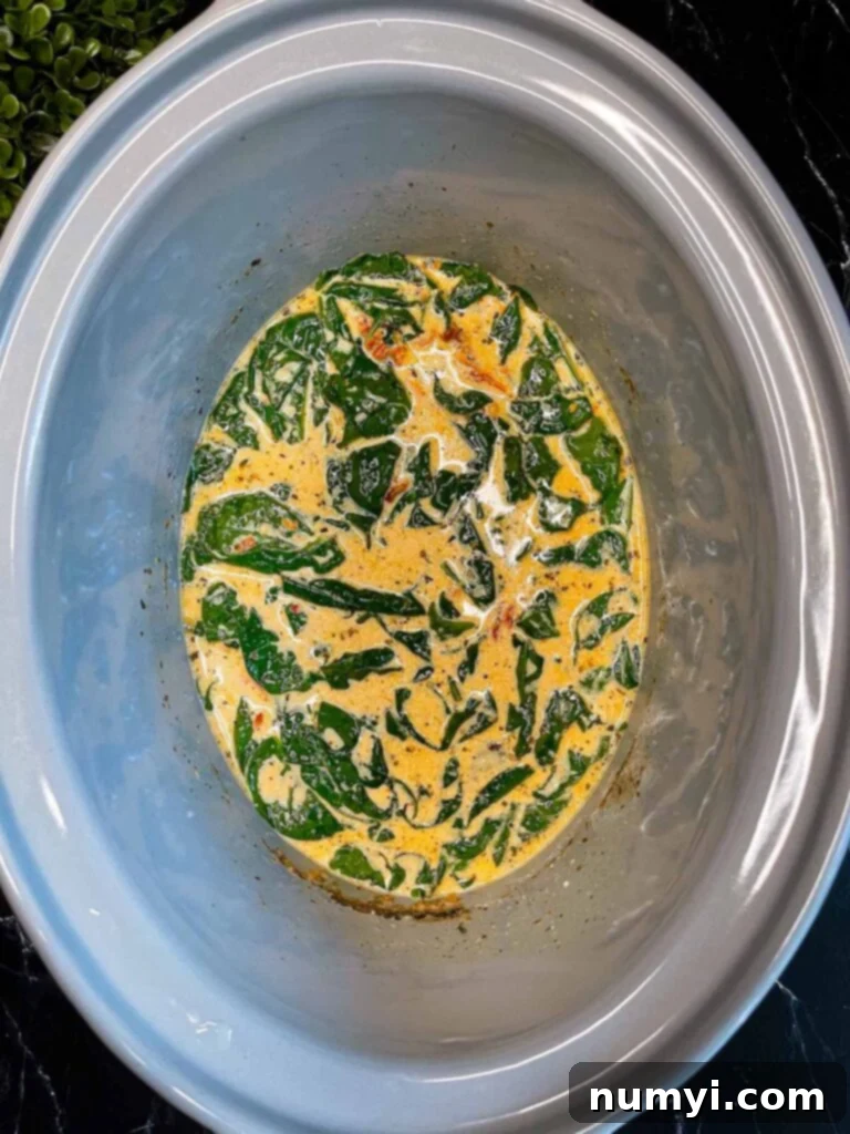 Creamy Slow Cooker Tuscan Chicken 11 Slow Cooker Tuscan Chicken sauce in a crock pot.