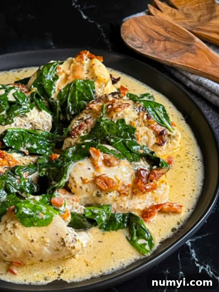 Creamy Slow Cooker Tuscan Chicken 12 Slow Cooker Tuscan Chicken in a dark bowl on a dark surface.