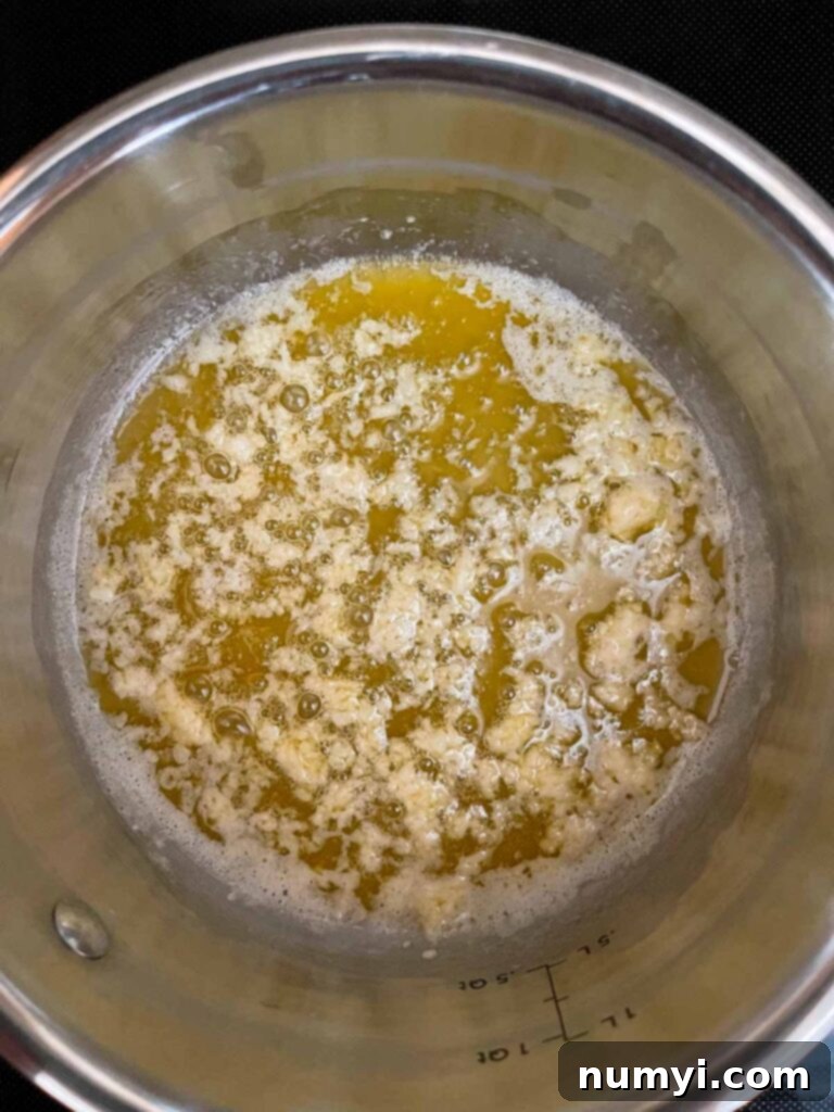 Creamy Slow Cooker Tuscan Chicken 5 Butter with herbs with garlic just added in a sauce pan.