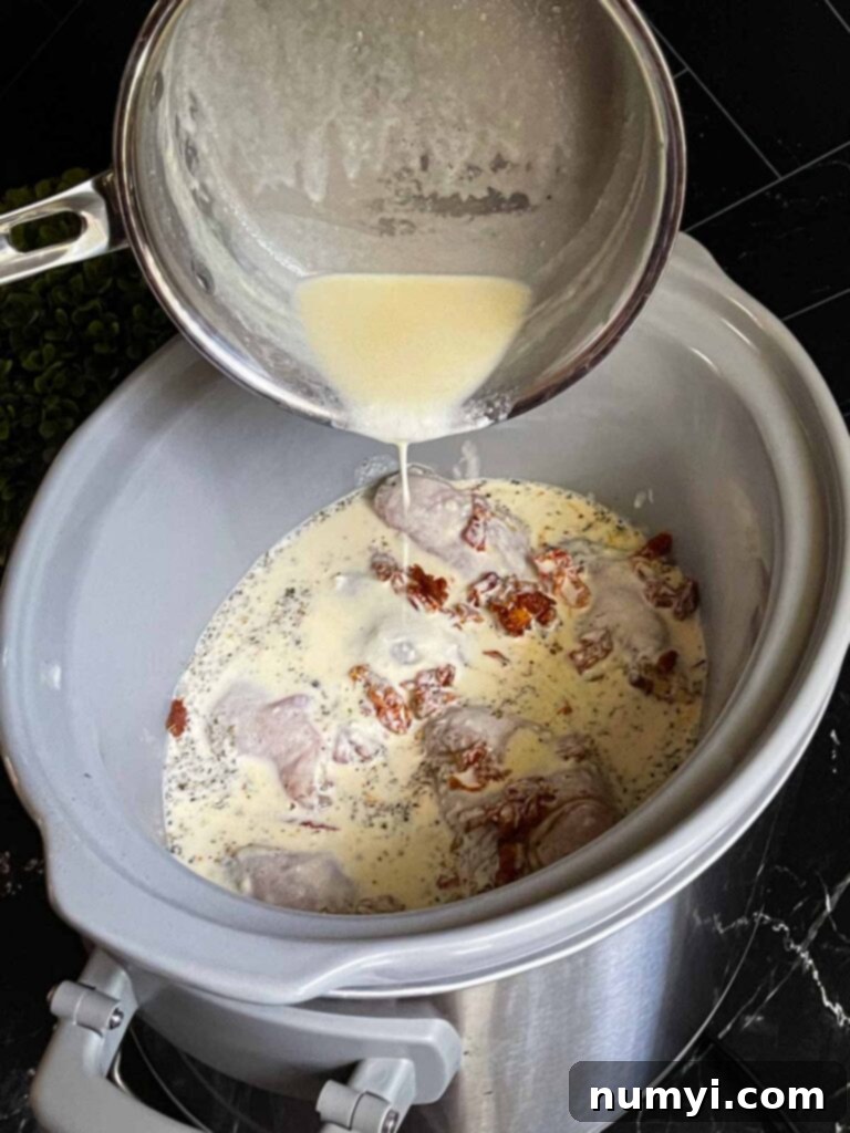 Creamy Slow Cooker Tuscan Chicken 8 Pouring the Tuscan chicken sauce over raw chicken in a slow cooker.