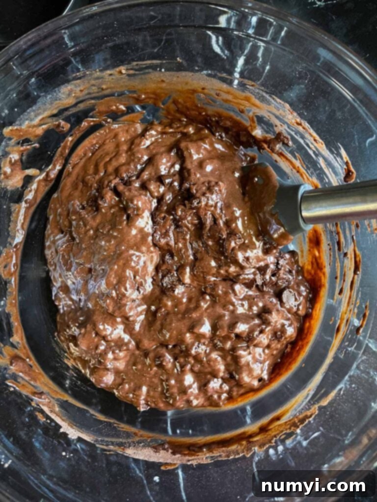 Mixing all the ingredients for double chocolate muffins in a large glass bowl.