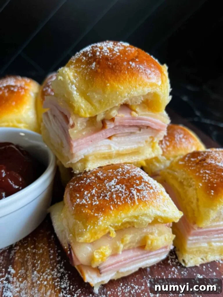 Whip Up Easy Monte Cristo Sliders for Your Next Bash 2 Monte Cristo sliders stacked up on a dark cutting board.