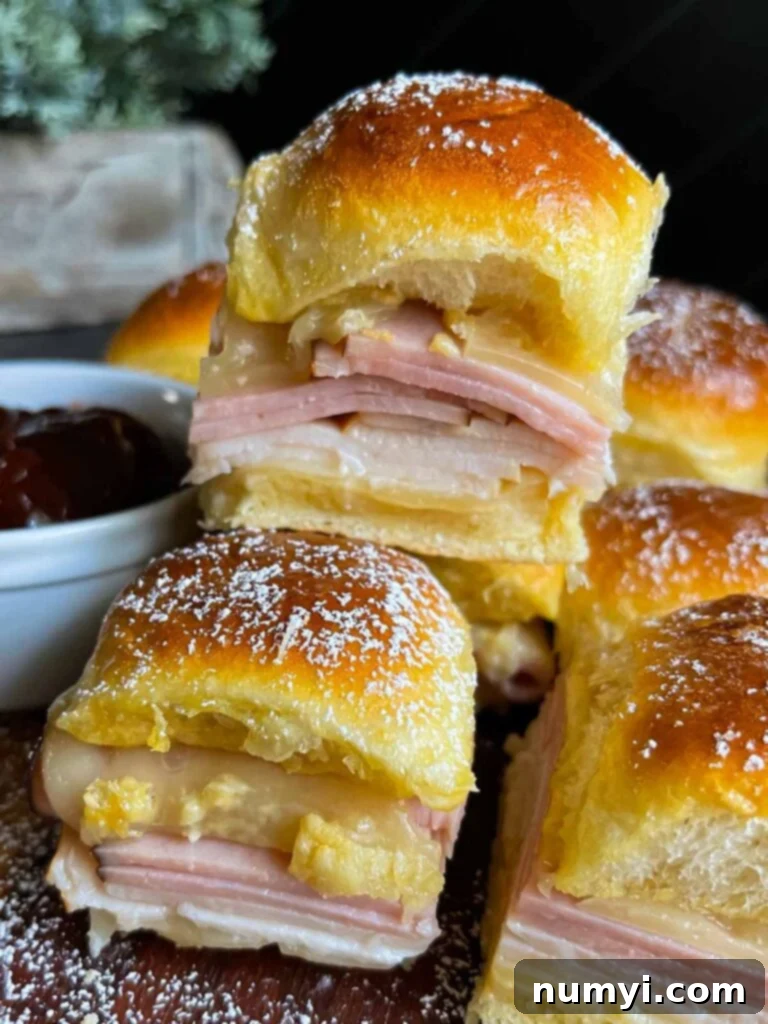 Whip Up Easy Monte Cristo Sliders for Your Next Bash 16 Monte Cristo sliders stacked up on a dark cutting board.