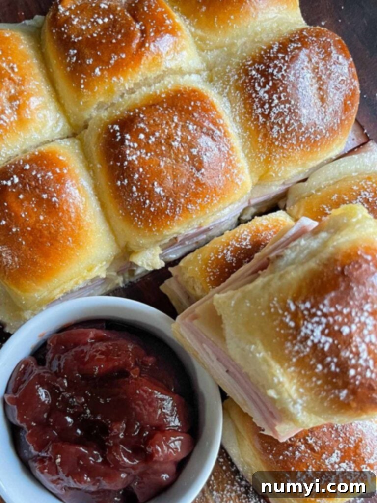 Whip Up Easy Monte Cristo Sliders for Your Next Bash 3 Monte Cristo sliders stacked up on a dark cutting board.