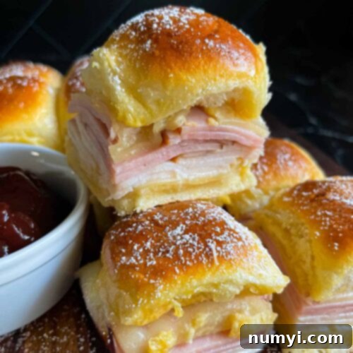 Whip Up Easy Monte Cristo Sliders for Your Next Bash 18 Monte Cristo sliders stacked up on a dark cutting board.