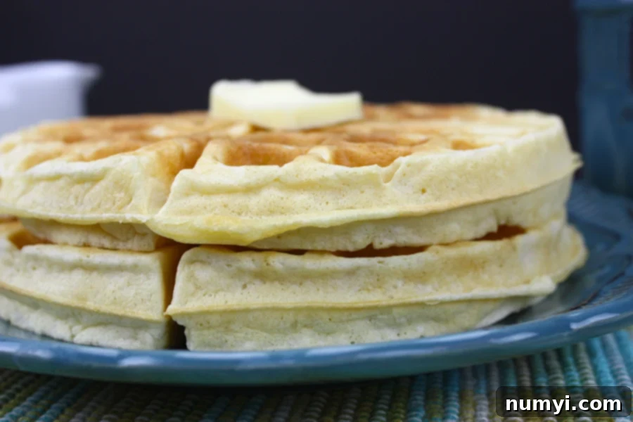 A stack of golden brown, round waffles on a vibrant blue plate, ready to be served.