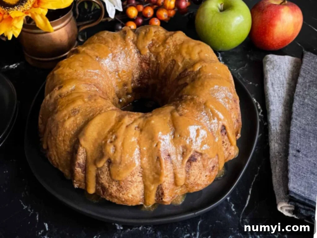 Caramel glazed apple dapple cake on a dark plate on a dark surface.
