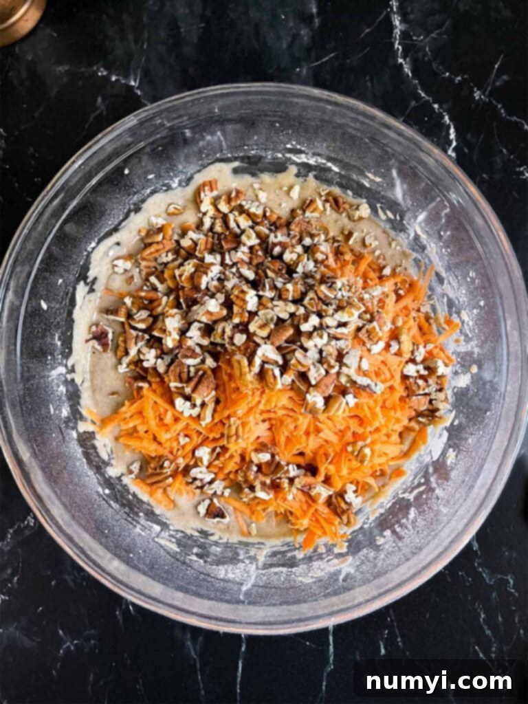 Spiced Sweet Potato Cake 7 Shredded sweet potato and toasted pecans added to the sweet potato cake mixture in a glass mixing bowl.