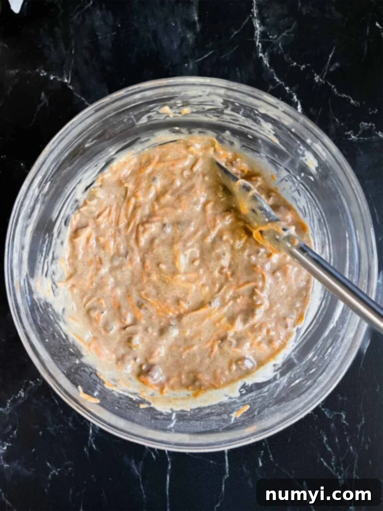 Spiced Sweet Potato Cake 8 Sweet potato cake batter in a glass mixing bowl on a dark surface.